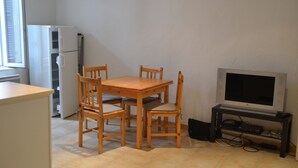 Una cocina compacta con una mesa de comedor y sillas, un refrigerador y un televisor sobre un mueble.