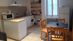 Una cocina compacta con lavadora, microondas y comedor con sillas de madera.
