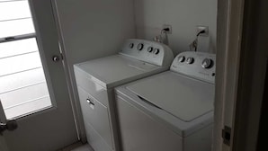 A laundry room with two white front-loading washing machines and dryers, a door, and a window. - RAGOL 502 ALMERIA MONTERREY MINUTOS DE AEROPUERTO (ALMERIA)