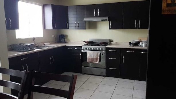 A compact kitchen with dark cabinets, a gas stove, a sink, and a window providing natural light. - RAGOL 502 ALMERIA MONTERREY MINUTOS DE AEROPUERTO (ALMERIA)