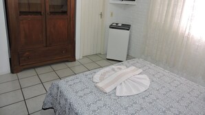 A bedroom with a bed, a wooden wardrobe, a white refrigerator, and a mounted TV. - Pousada Don Alberto's (Florianópolis)