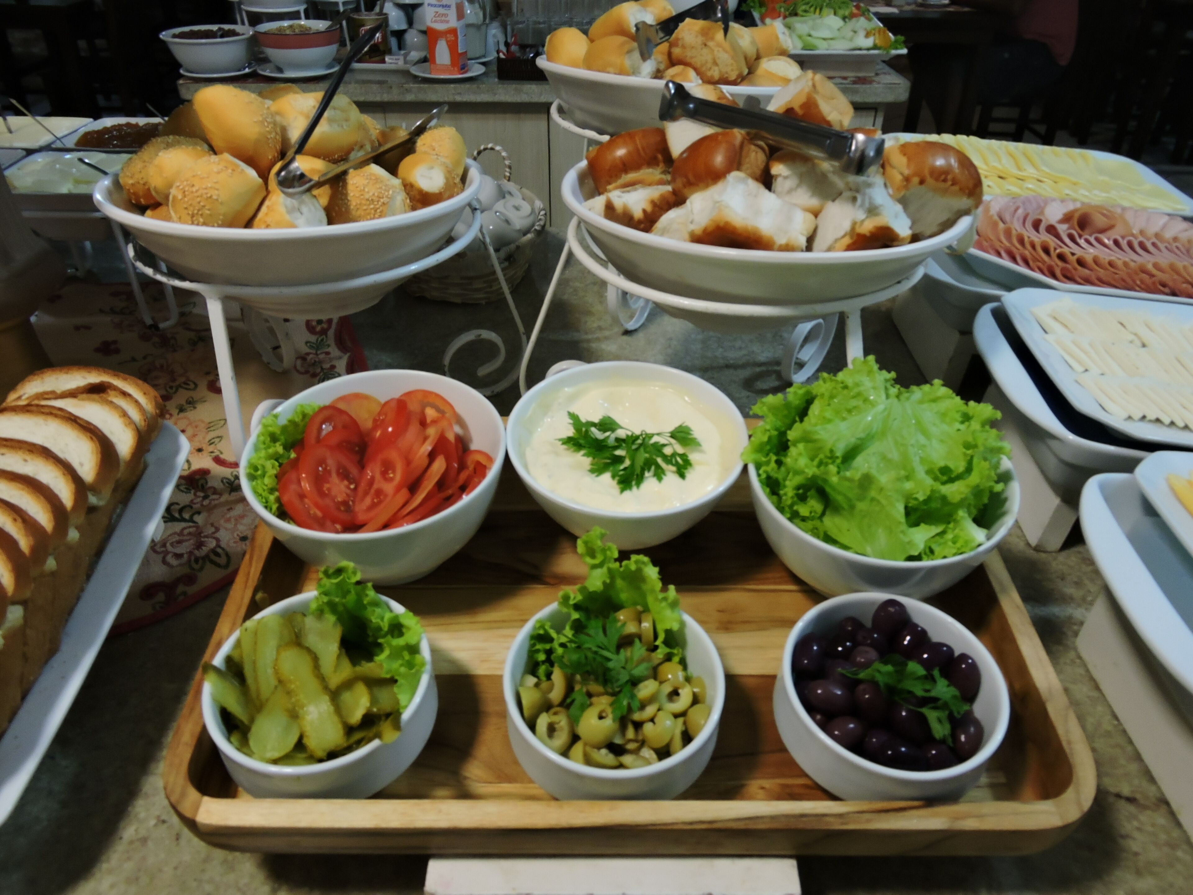 A buffet table with various food items including bread, salads, and dips.