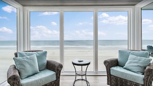 Ein Zimmer mit Korbmöbeln und Blick auf den Strand.