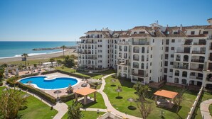Ein mehrstöckiges Hotel mit Pool, Blick auf den Strand und einem gepflegten Garten.