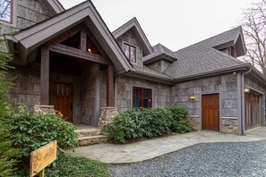 A stone house with a stone staircase, wooden doors, and a gravel driveway.