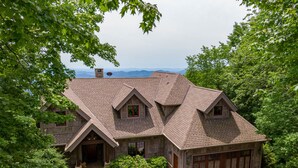 Ein Haus aus Stein mit geneigtem Dach, einer Garage und einer Auffahrt.