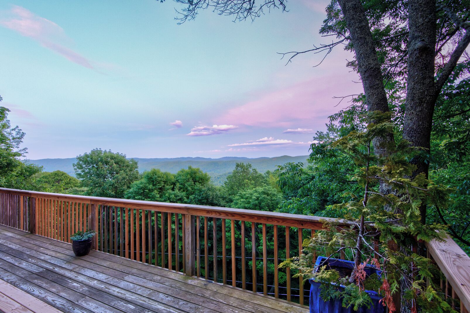 A wooden deck with a view of a forest and distant mountains.