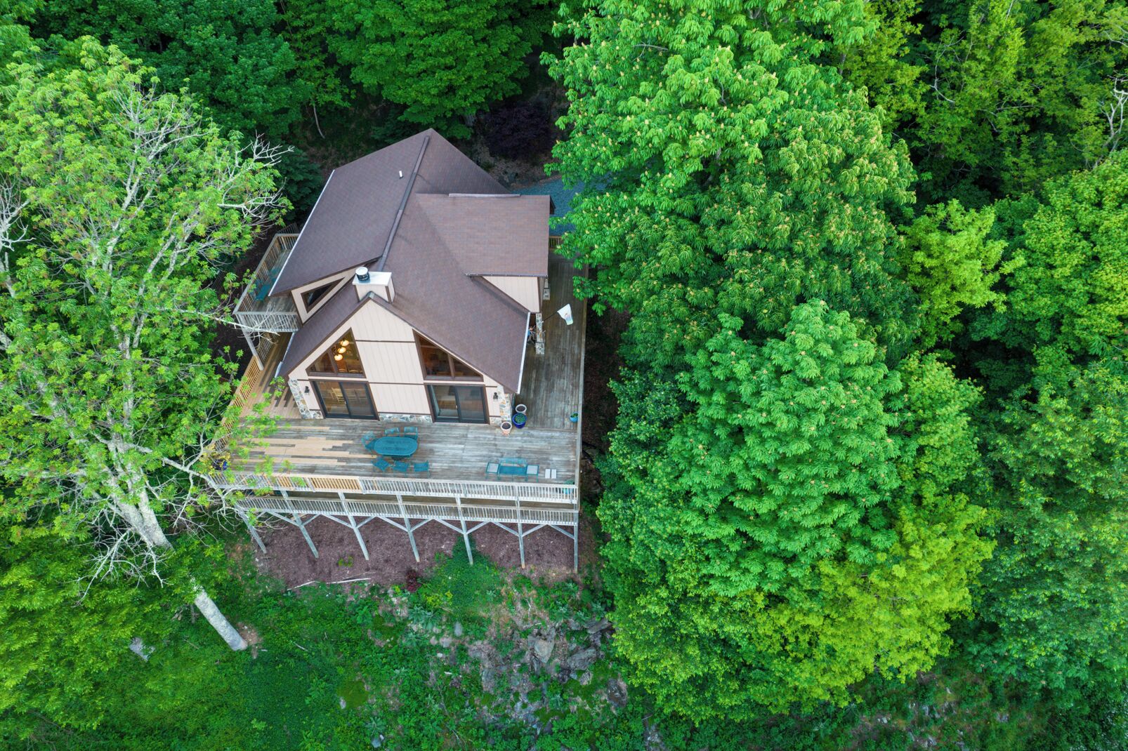 An aerial view of a house surrounded by dense green trees.
