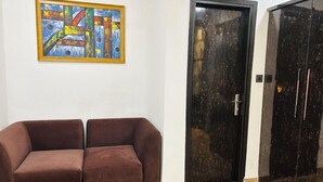A room with a brown sofa, a black door, and a framed abstract painting on the wall. - Cosmo Hotel (New Delhi)