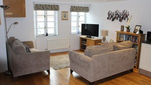 A living room with two sofas, a TV, a bookshelf, and a radiator.