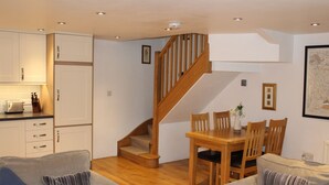 A compact living space with a kitchen, dining area, and a staircase.