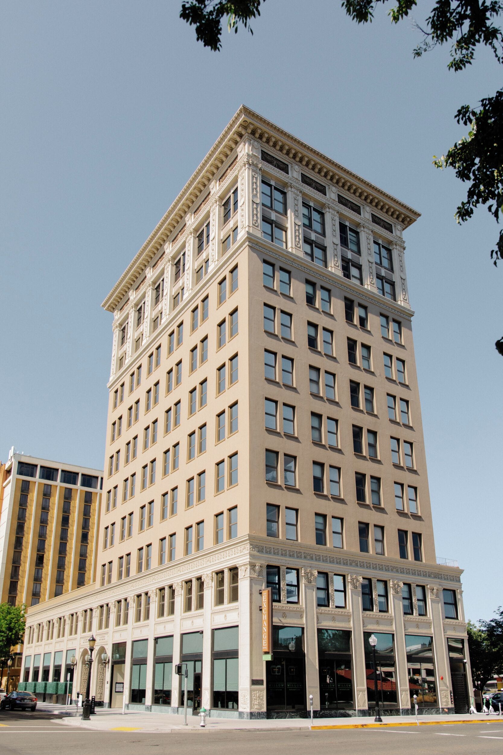 A tall, beige building with a symmetrical facade, large windows, and a prominent entrance with a canopy.