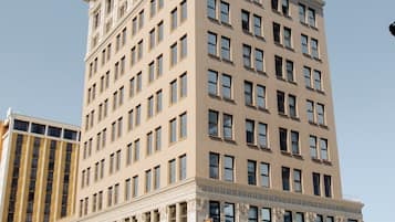 A tall, beige building with a symmetrical facade, large windows, and a prominent entrance with a canopy.