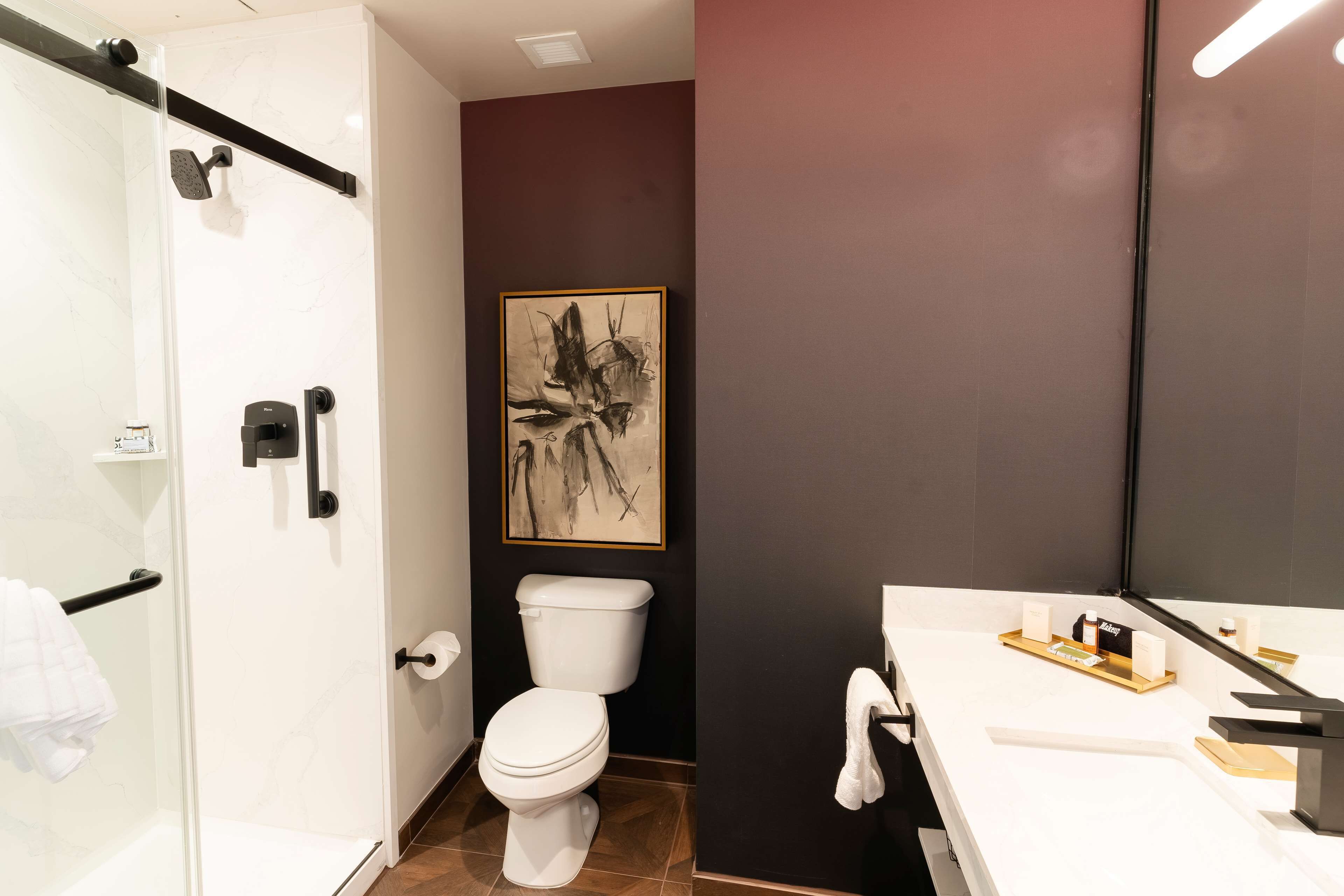 A modern bathroom with a glass shower enclosure, a white toilet, and a sink with a vanity.