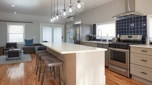 Une cuisine moderne dotée d’un îlot central, d’appareils électroménagers en acier inoxydable et d’un coin bar avec des tabourets.