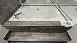 A modern bathroom with a freestanding bathtub, a shower area, and a tiled floor. - Embassy Inn (Hohenwald)