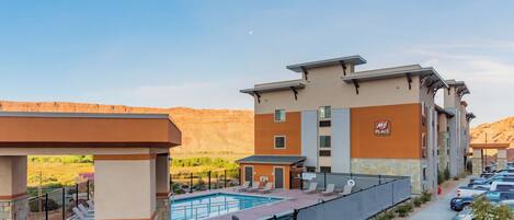 Un hotel con piscina, asientos al aire libre y vistas a las montañas.