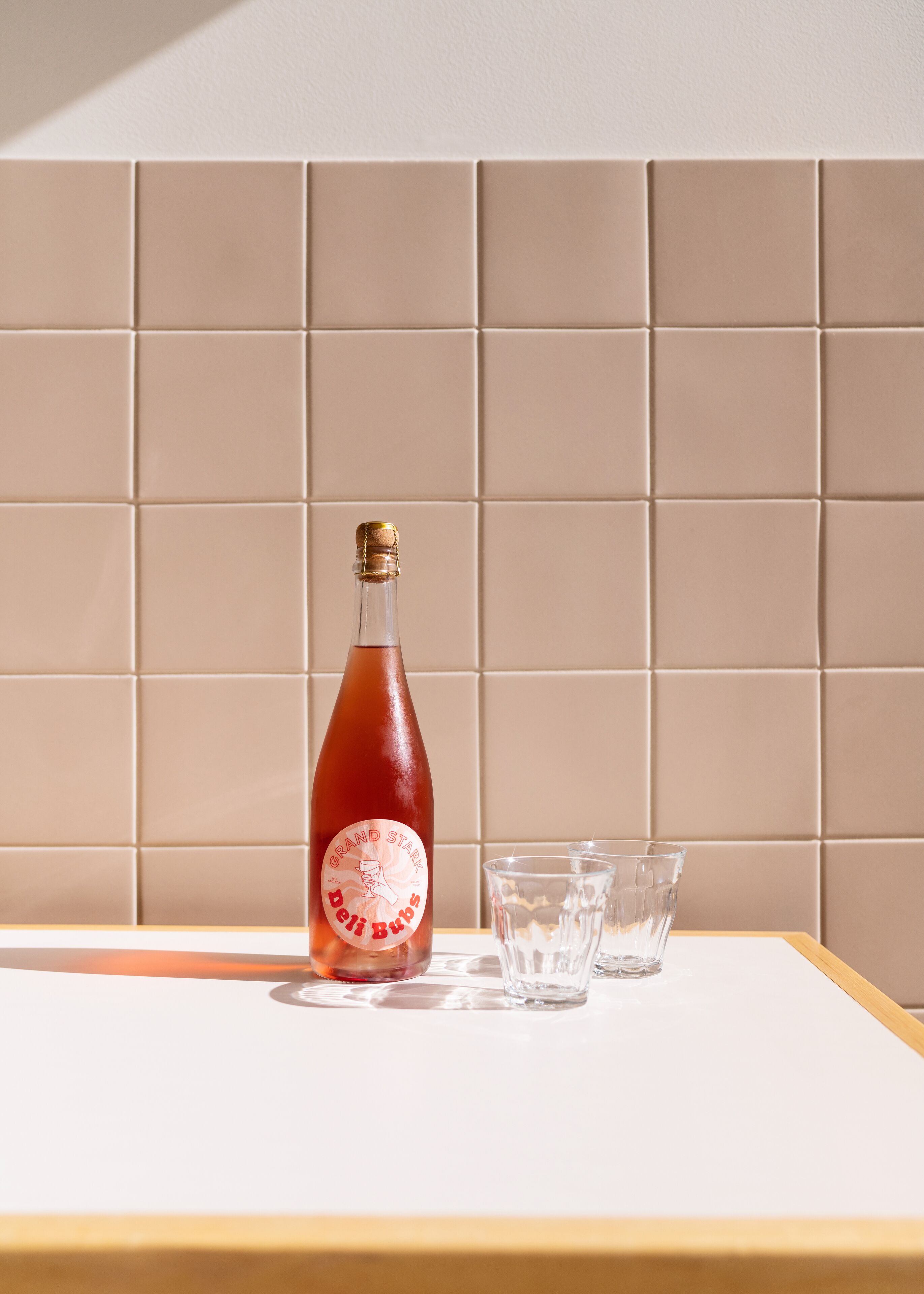 Una botella de Grand Stark Delis Bups sobre una mesa con tres vasos.