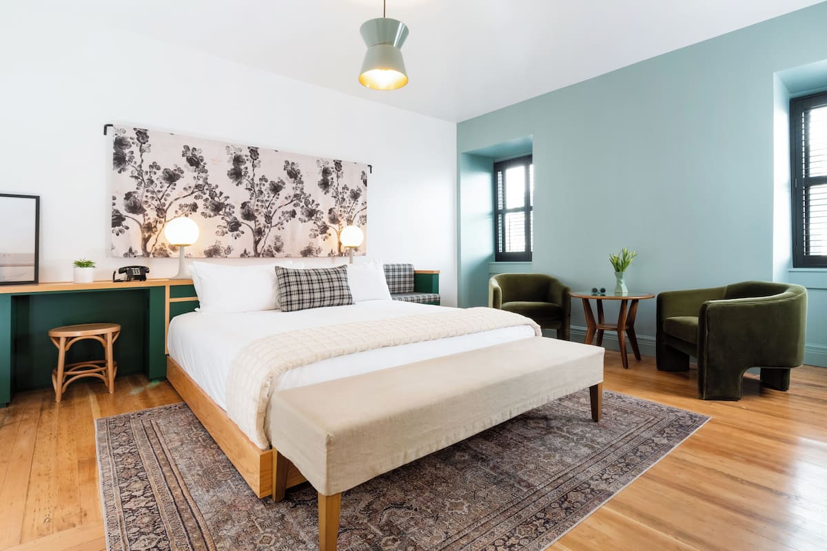 A modern bedroom with a bed, bedside tables, a desk, a chair, and a window.
