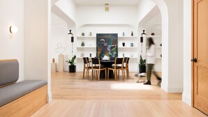 A modern dining area with a round table, wooden chairs, and a large painting on the wall.