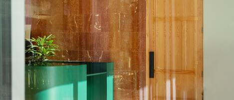 A modern lobby with a wooden floor, a green reception desk, and a marble wall.