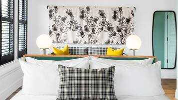Une chambre à coucher moderne avec un lit, deux lampes de chevet, une tapisserie à motifs floraux et une porte verte.