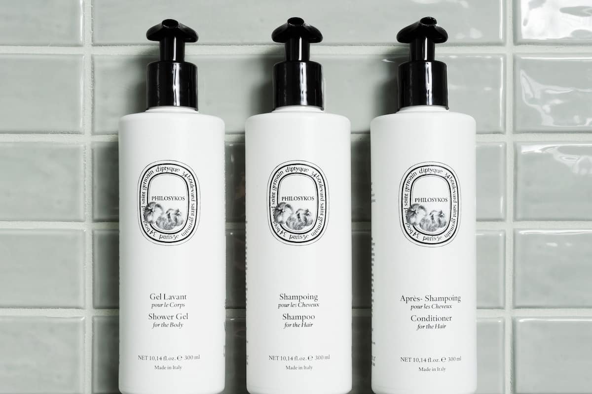Three white bottles with black pumps, labeled as PHILOSYKO'S, against a tiled wall.