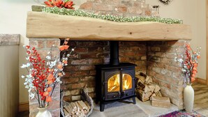 Una chimenea con pared de ladrillo, repisa de madera y flores decorativas.
