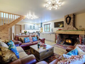 A spacious living room with a fireplace, leather sofas, a wooden coffee table, and a staircase.