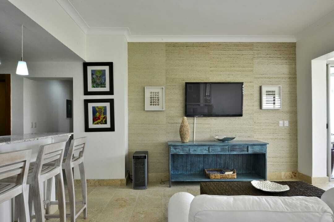 A modern living room with a flat-screen TV mounted on a textured wall, a blue console table, and a white sofa.