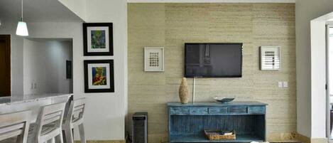 A modern living room with a flat-screen TV mounted on a textured wall, a blue console table, and a white sofa.