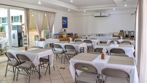 A dining area with tables and chairs, an air conditioning unit, and a kitchen visible through an open door. - 202 Junior Suite w/balcony & living area. (Isla Mujeres)