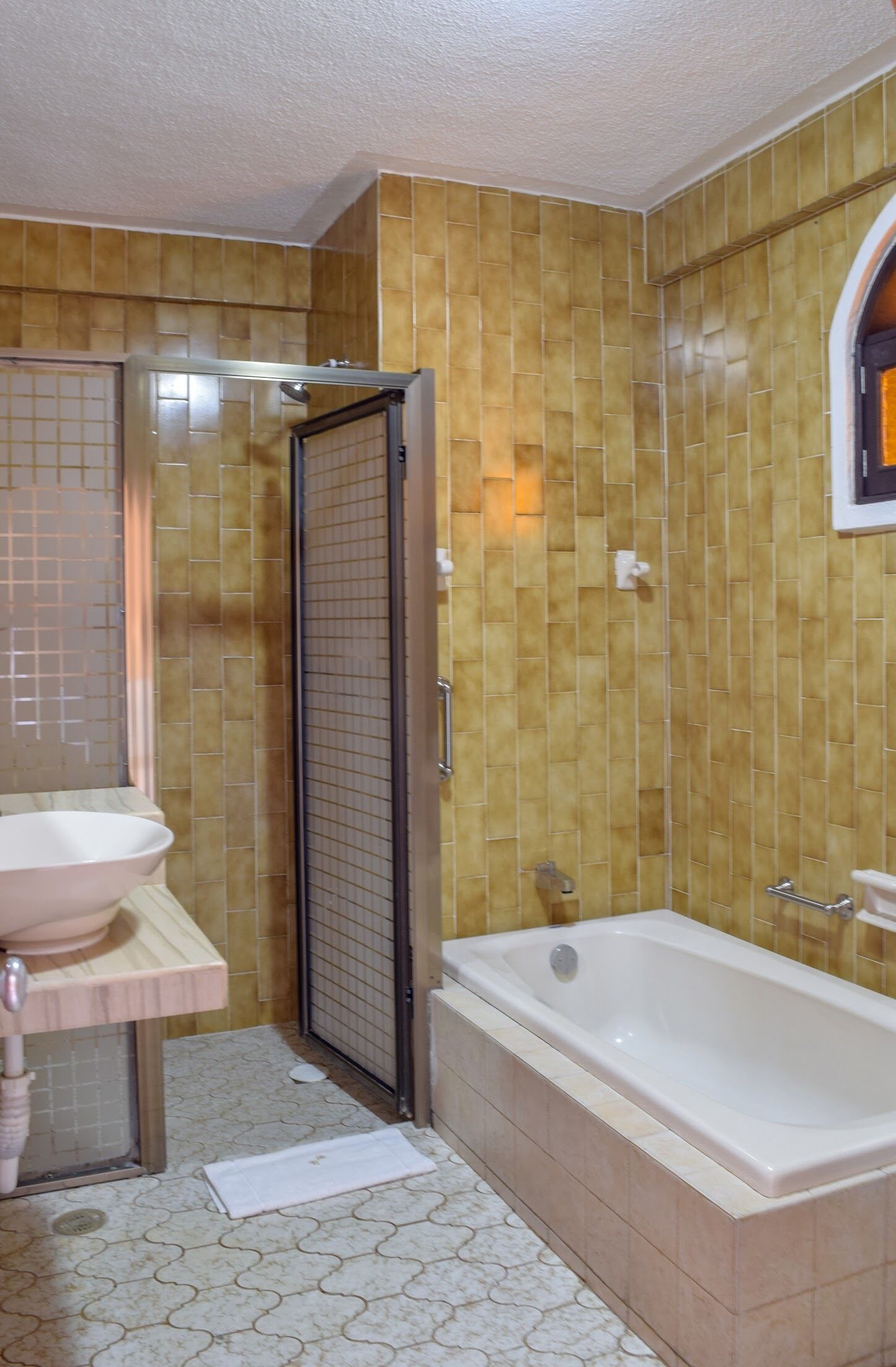 A bathroom with a bathtub, a sink, and a shower area.