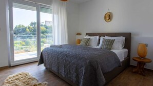 Una camera da letto con un letto grande, vista attraverso una porta scorrevole in vetro e un tavolino rotondo con una lampada.