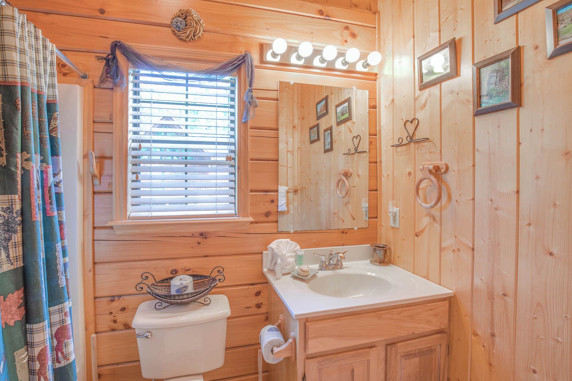 A wooden cabin bathroom with a toilet, sink, and mirror.