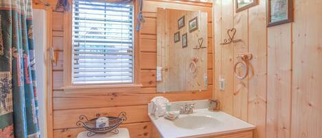 A wooden cabin bathroom with a toilet, sink, and mirror.