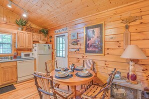 A wooden cabin interior with a kitchen, dining area, and a framed artwork on the wall. - Bear Escape by Jackson Mountain Rentals (Sevierville)