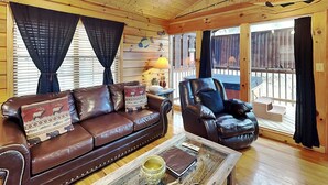 L’intérieur d’un chalet chaleureux, avec un canapé en cuir marron, une table basse en verre et un fauteuil en cuir.