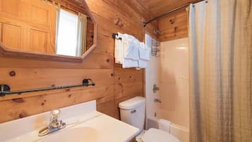 A wooden cabin bathroom with a sink, toilet, and shower.
