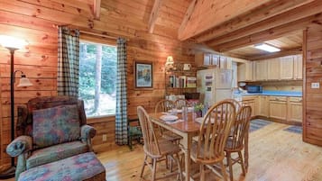 A wooden cabin interior with a dining area, a sofa, and a kitchen.