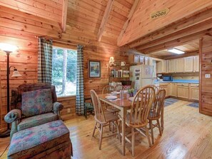 A wooden cabin interior with a dining area, a sofa, and a kitchen. - Bear's Den by Jackson Mountain Rentals (Gatlinburg)
