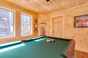 A pool table with balls in a wooden room with large windows and a door. - Back to Nature by Jackson Mountain Rentals (Gatlinburg)