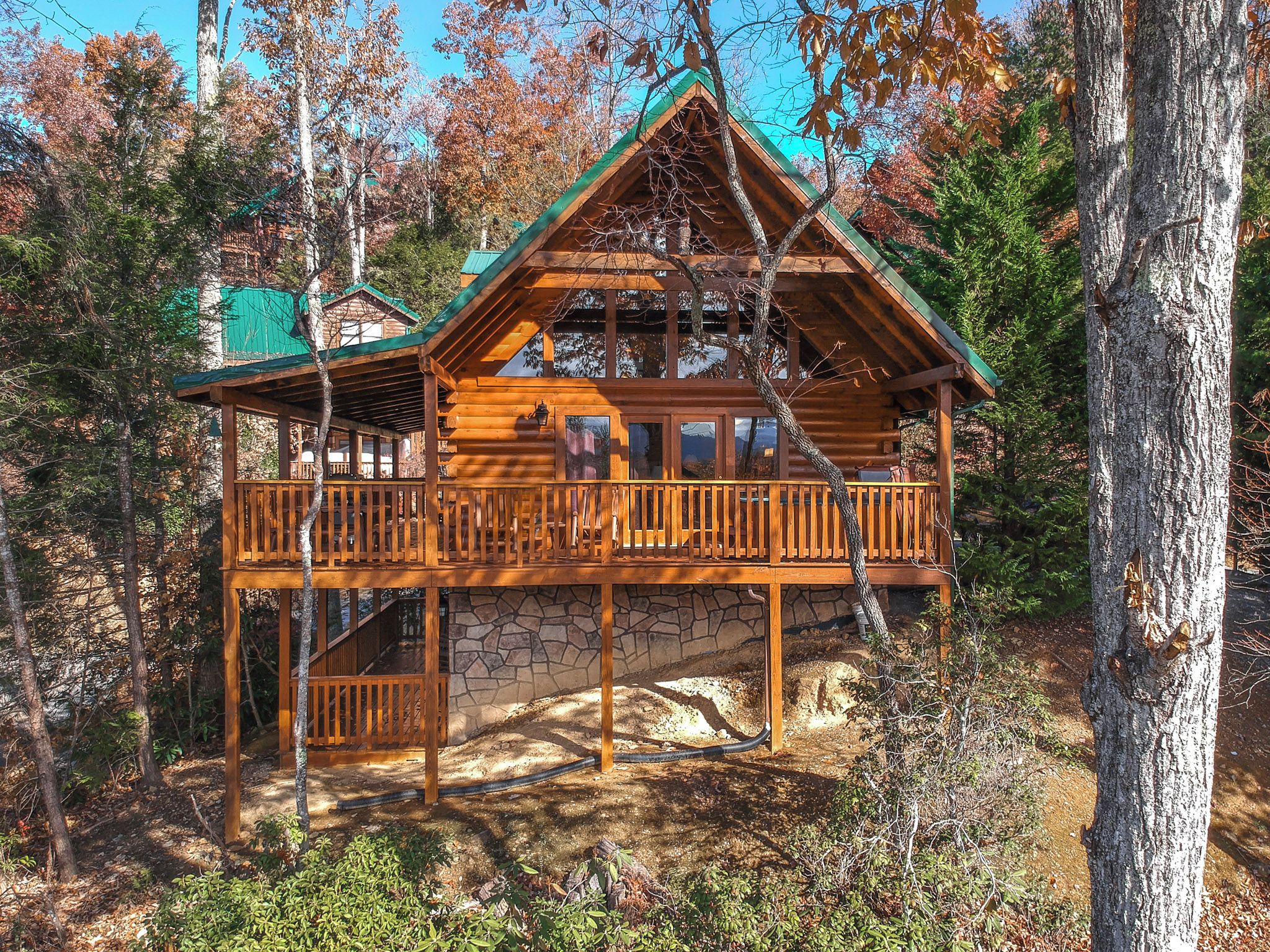 A wooden cabin with a stone foundation, a balcony, and a staircase leading to the upper level.