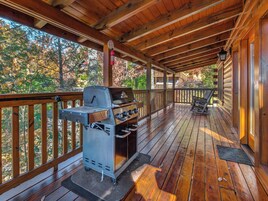Una terraza cubierta de madera con una parrilla y mobiliario para exteriores.