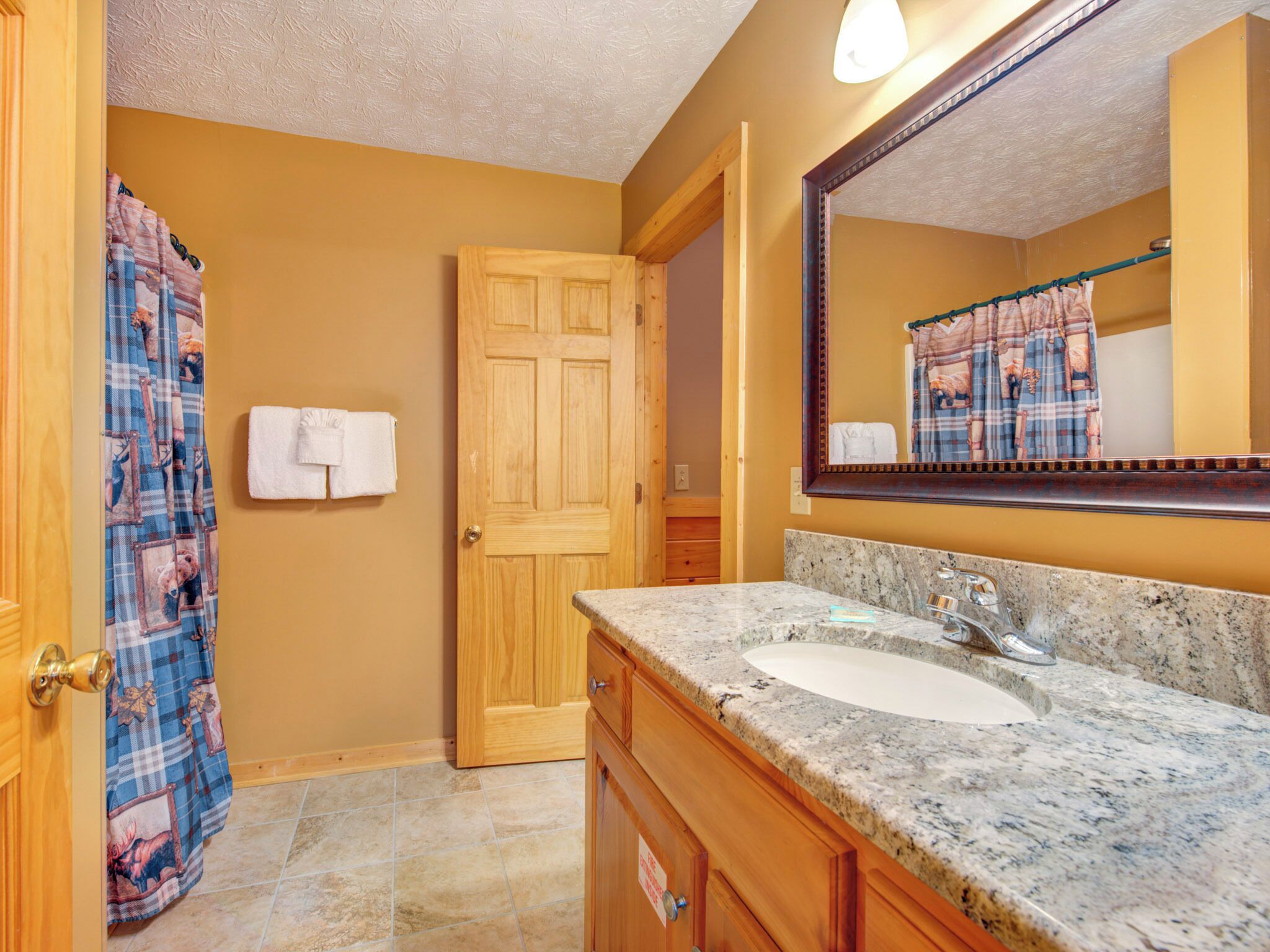 Une salle de bain avec une porte en bois, un lavabo en marbre et un miroir.
