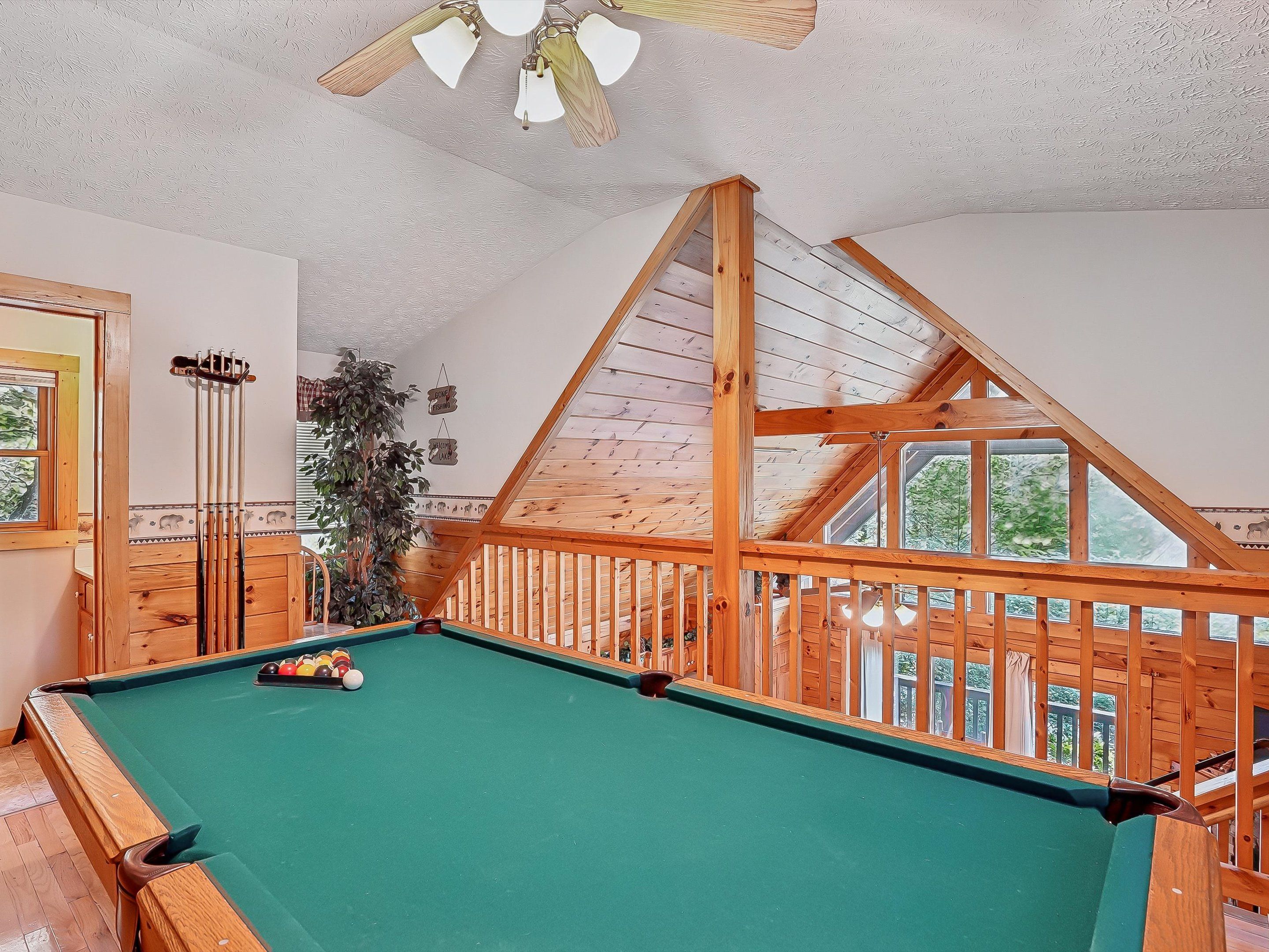 A pool table in a room with wooden beams and a sloped ceiling.