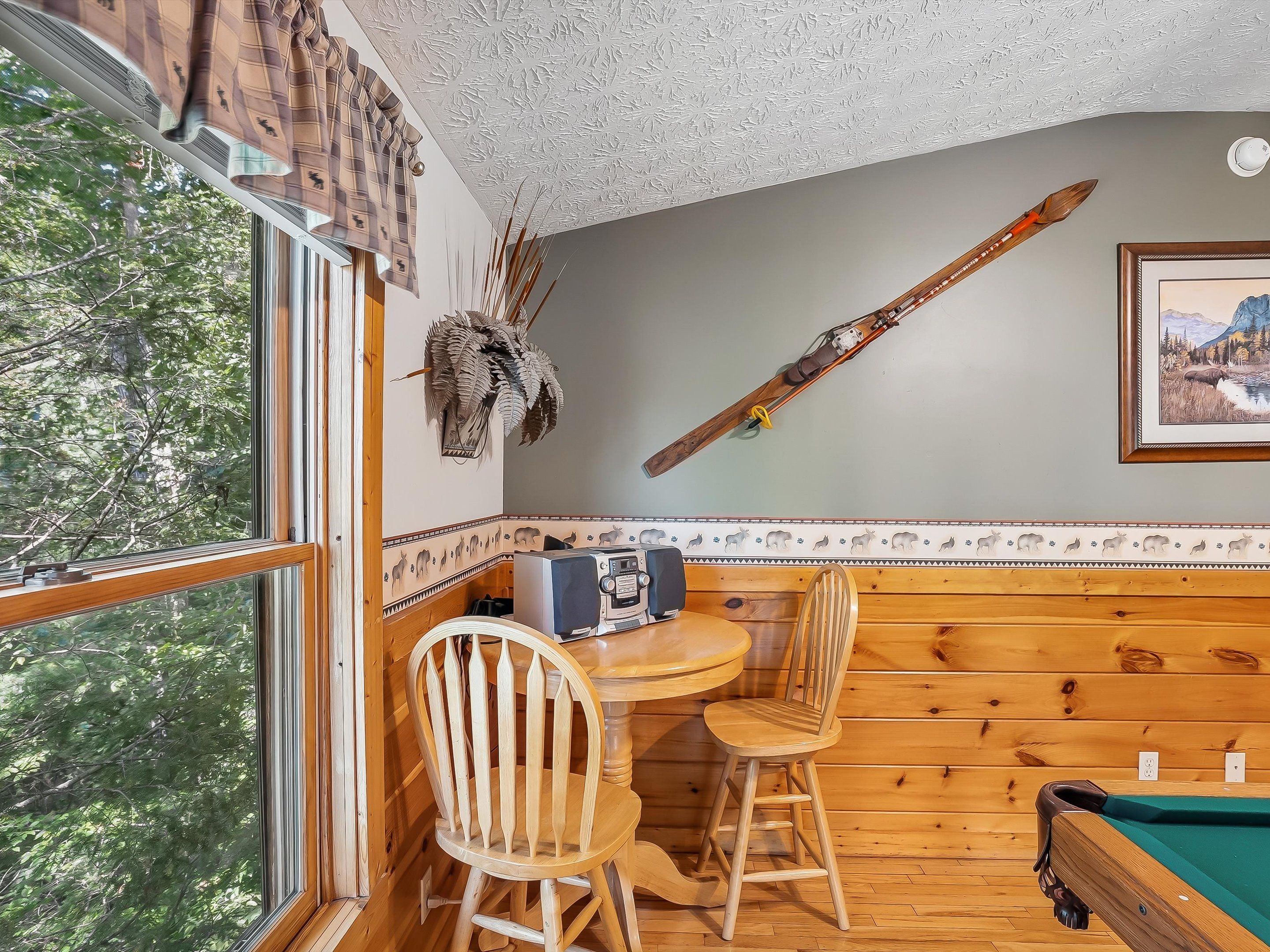 A wooden interior with a dining area, a pool table, and a ski on the wall.