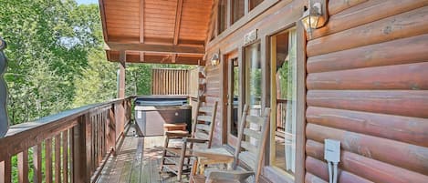 Une terrasse en bois avec un jacuzzi, des sièges et un espace abrité.
