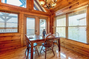 Un interior de madera con una mesa de comedor, sillas y una araña.