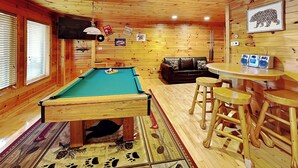 A wooden interior with a pool table, a sofa, and a bar area. - Cloud Dancer by Jackson Mountain Rentals (Gatlinburg)
